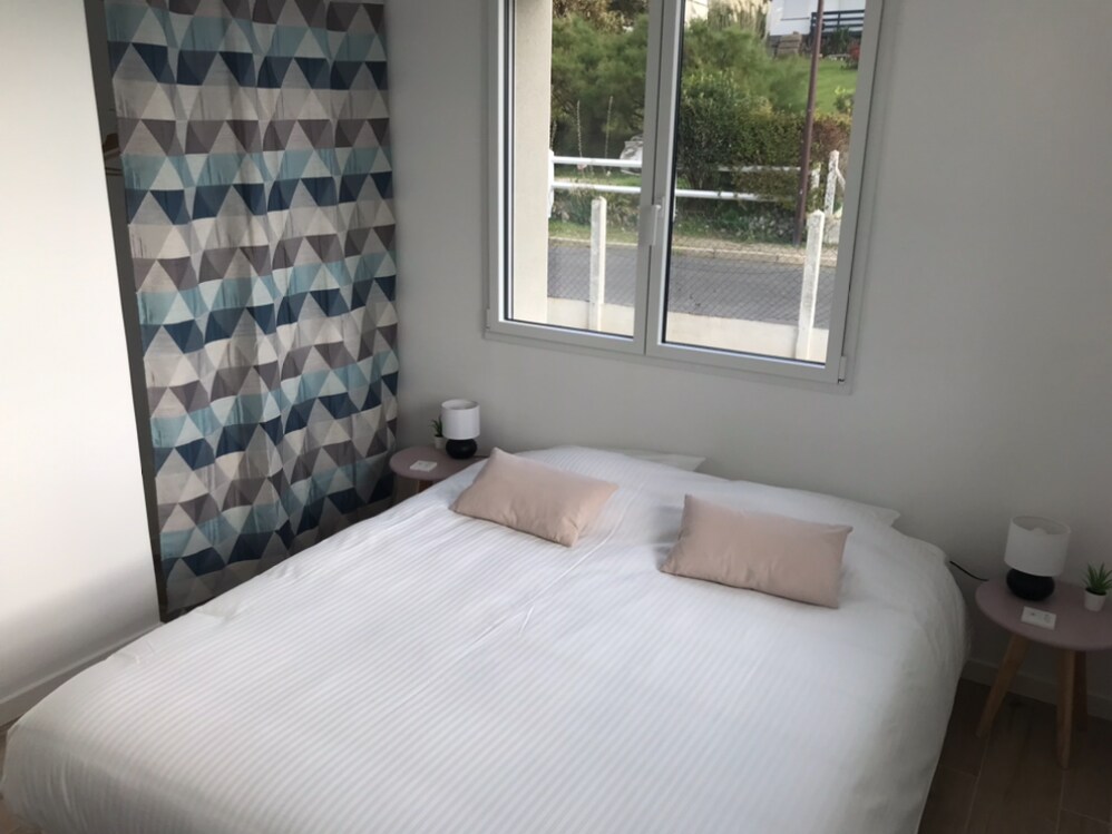 Chambre beige avec rideau géométrique et deux lits simples